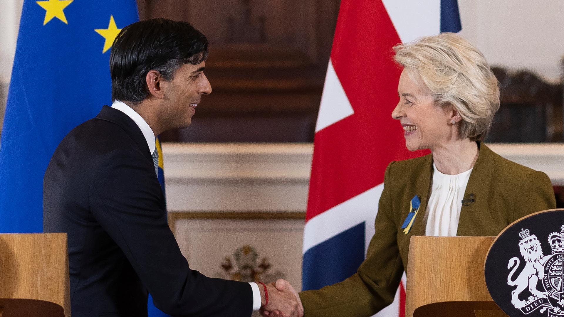 Der Regierungs-Chef von dem Land Groß-Britannien, Rishi Sunak, und die Präsidentin von der Europäischen Union, Ursula von der Leyen. Sie schütteln sich die Hände. 