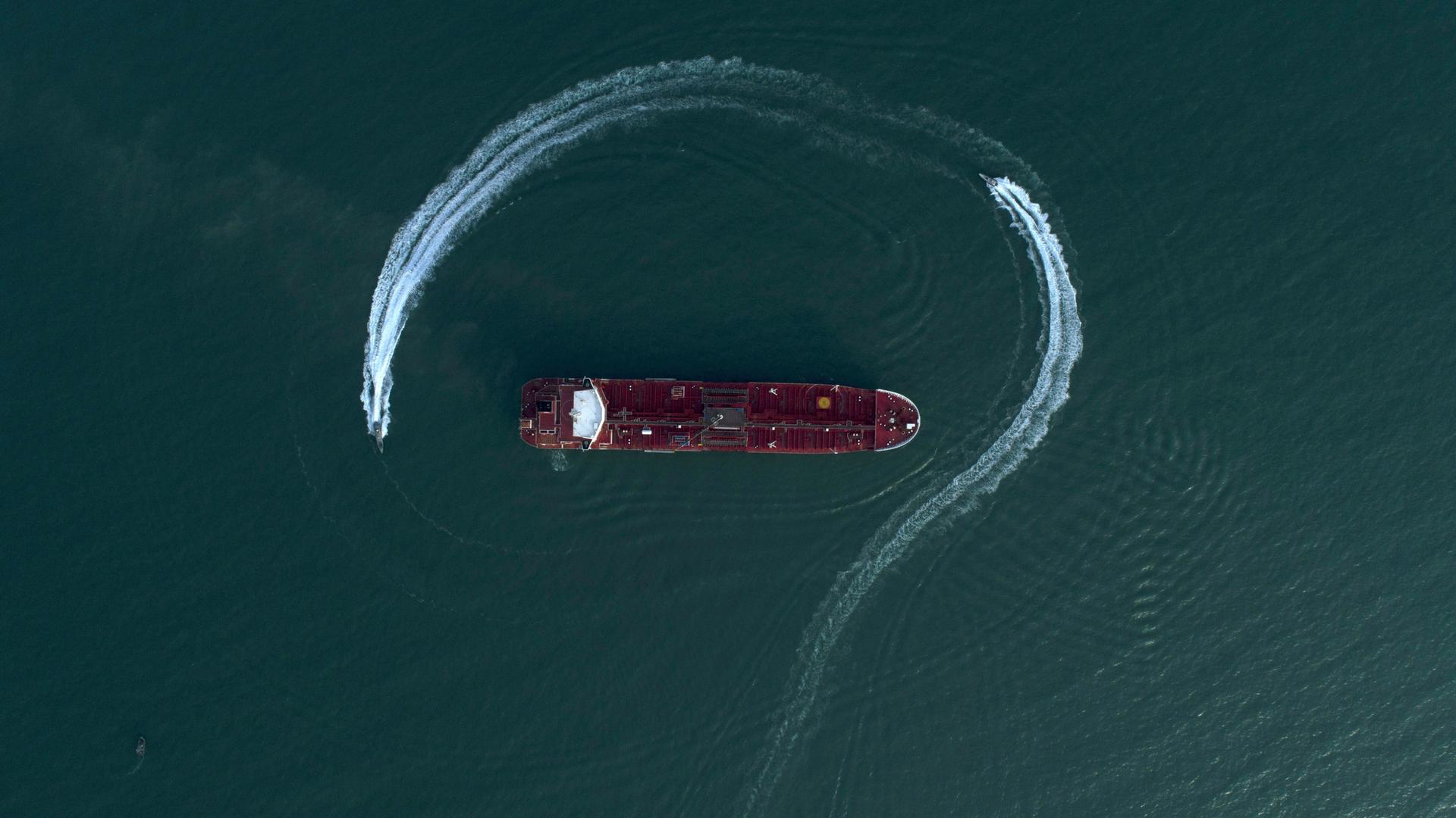 Ein Öltanker aus der Luftaufsicht auf blauem Meerwasser, umrundet von einem Schnellboot Ein Öltanker aus der Luftaufsicht auf blauem Meerwasser, umrundet von einem Schnellboot