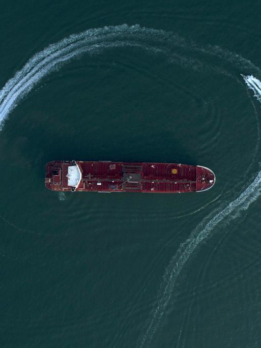 Ein Öltanker aus der Luftaufsicht auf blauem Meerwasser, umrundet von einem Schnellboot Ein Öltanker aus der Luftaufsicht auf blauem Meerwasser, umrundet von einem Schnellboot