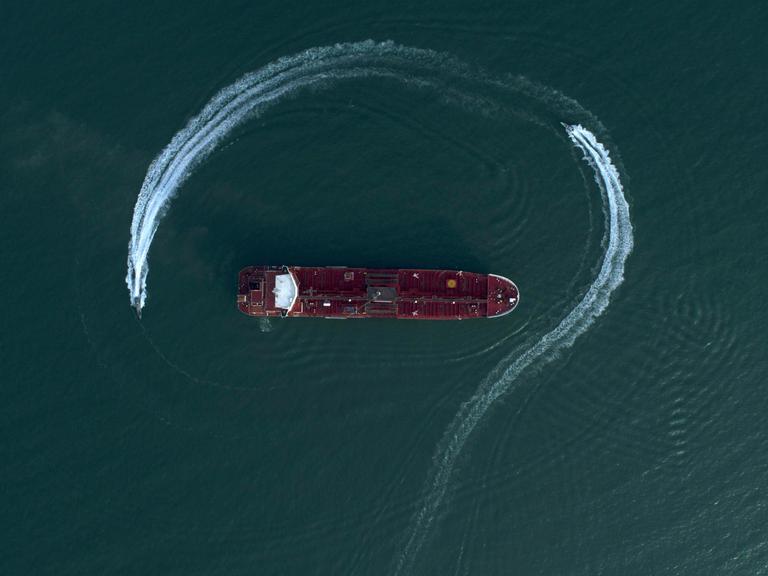 Ein Öltanker aus der Luftaufsicht auf blauem Meerwasser, umrundet von einem Schnellboot Ein Öltanker aus der Luftaufsicht auf blauem Meerwasser, umrundet von einem Schnellboot