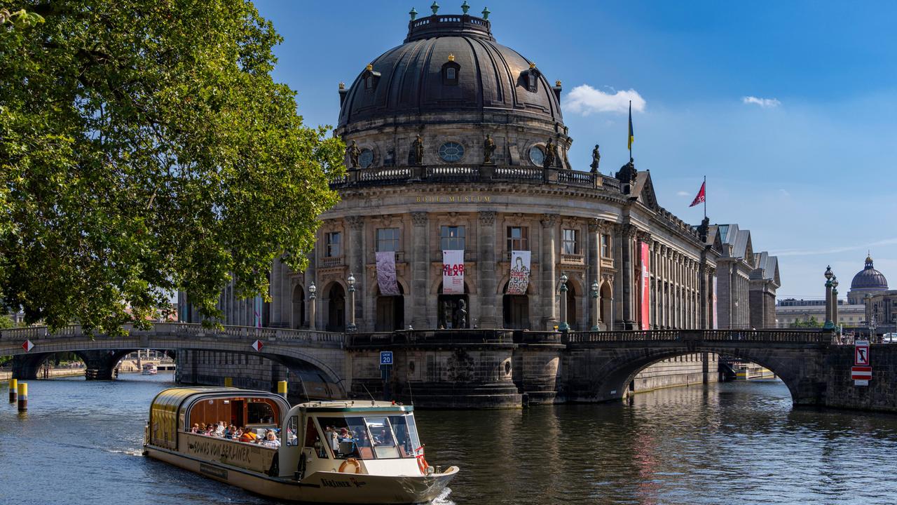 Blick auf die Spree mit Ausflugsboot und die dahinter liegende Berliner Museumsinsel mit dem Bode-Museum.