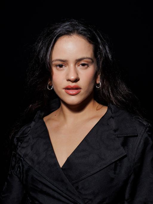 Die spanische Sängerin Rosalía auf einem Porträtfoto vor schwarzem Hintergrund. Sie trägt ein schwarzes Kleid, zu sehen sind vor allem ihr Gesicht und Dekolleté.