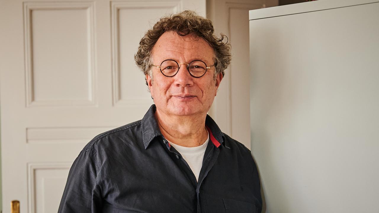 Schriftsteller Ingo Schulze lehnt in seiner Wohnung in Charlottenburg an einem Schrank.