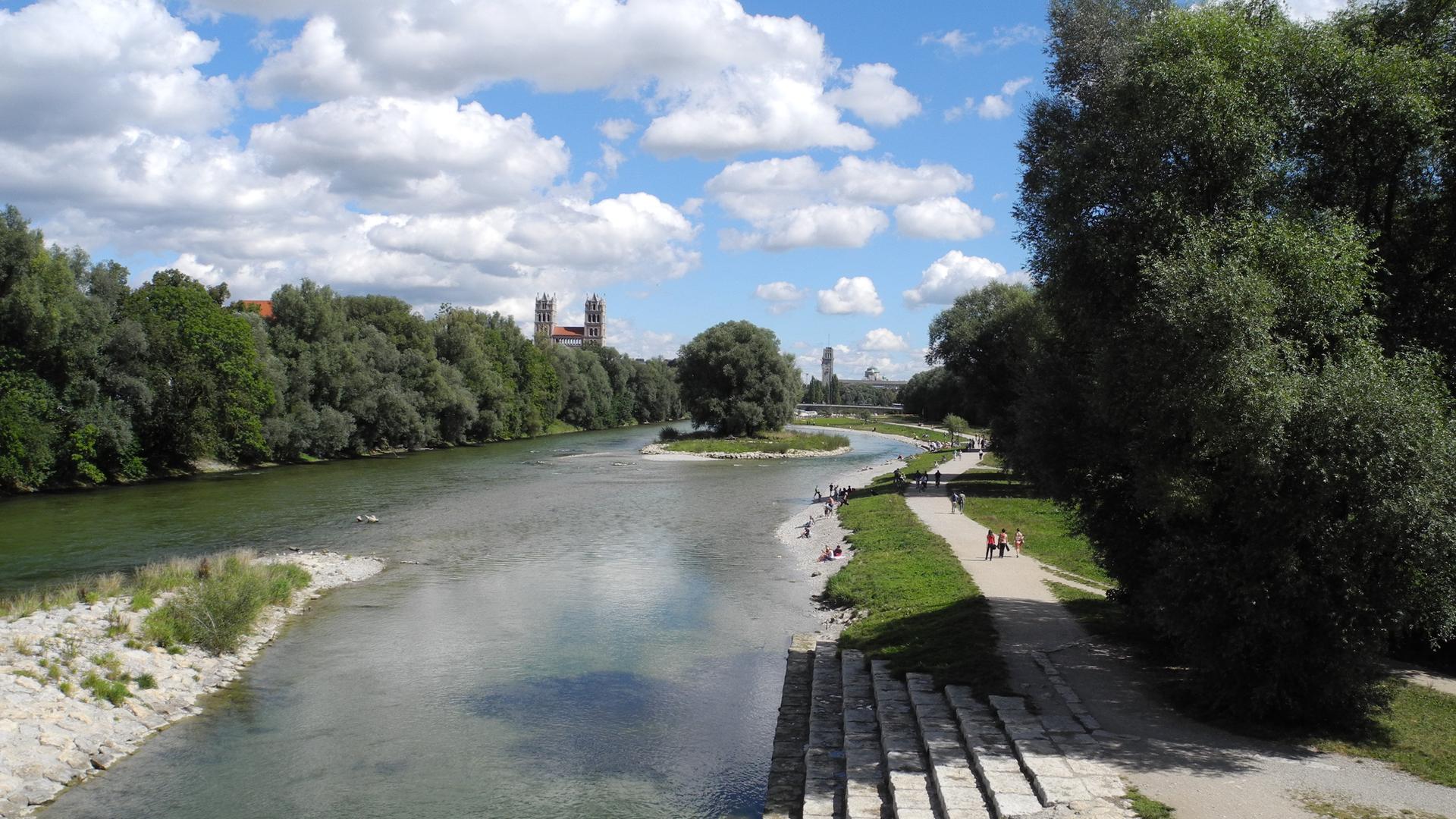 Eine Terrasse am renaturierten Isarstrand, im Hintergrund eine Brücke und eine Kirche.