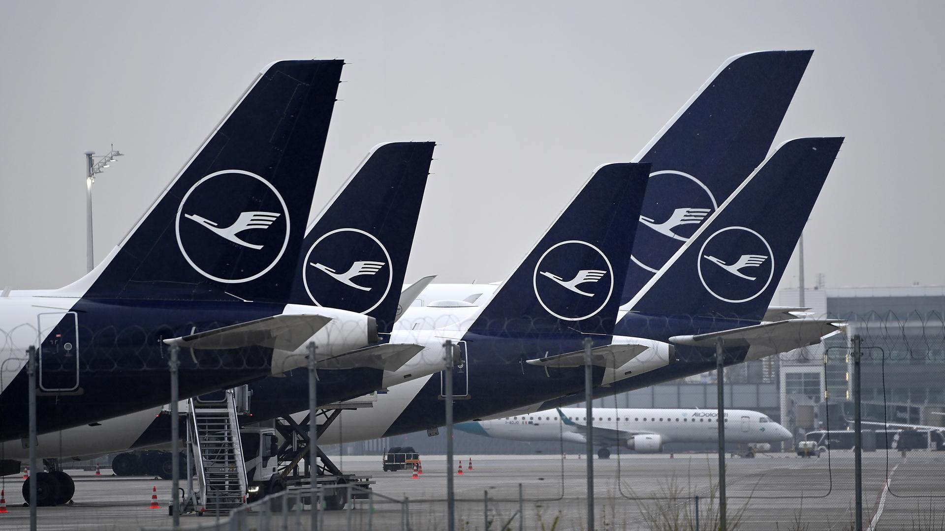 Mehrere Flugzeuge der Lufthansa stehen nebeneinander auf einem Flug-Hafen.