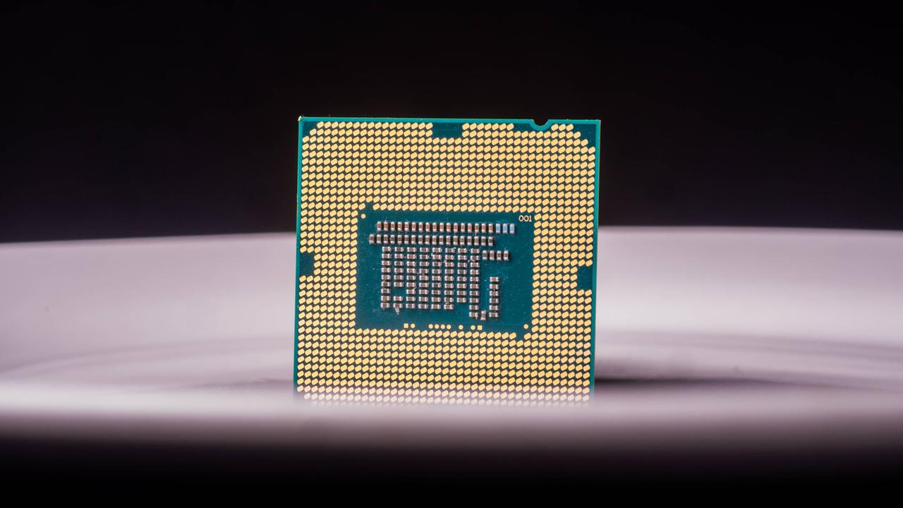 Nahaufnahme eines Computerchips auf einer fliederfarbenen Fläche vor einem dunklen Hintergrund.