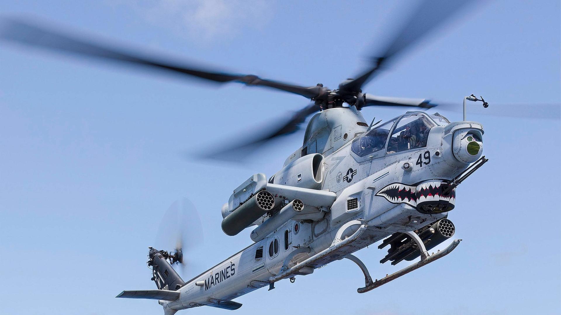 Ein Kampfhubschrauber bekommt von einem Mann an Bord eines großen Schiffes der Marine das Signal zur Landung auf dem Deck. Ein Kampfhubschrauber bekommt von einem Mann an Bord eines großen Schiffes der Marine das Signal zur Landung auf dem Deck.