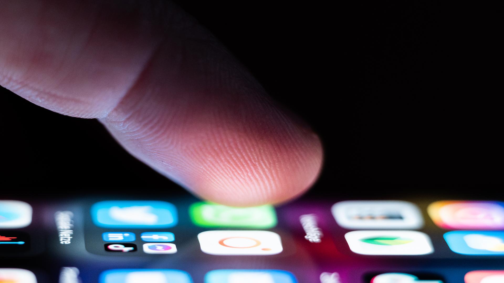 Ein Finger zeigt auf Apps auf einem Handy. Ein Finger zeigt auf Apps auf einem Handy.