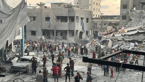 Menschen versammeln sich vor einem Gebäude, das bei einem israelischen Luftangriff westlich von Gaza-Stadt beschädigt wurde.