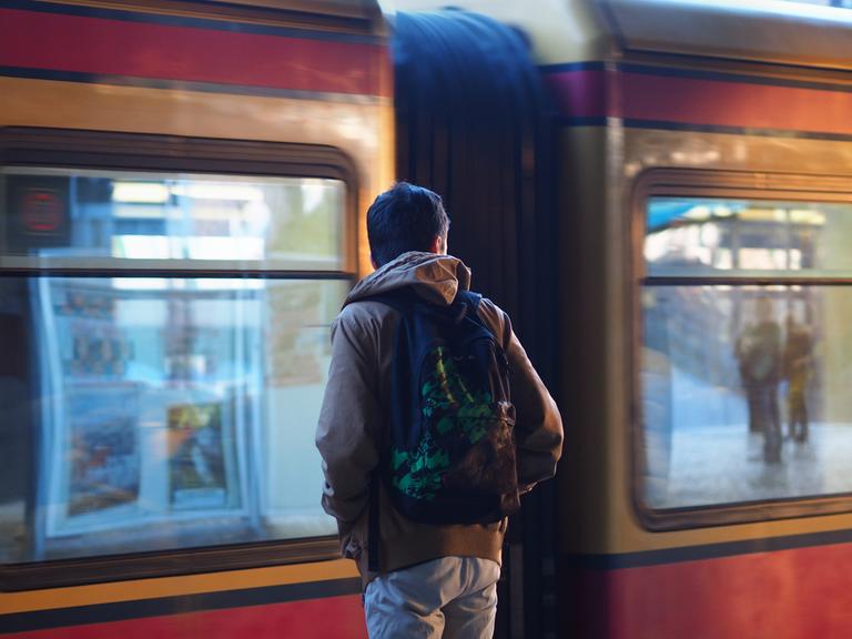 Ein junger Migrant mit einem Rucksack steht auf einem S-Bahn-Gleis in Berlin.
