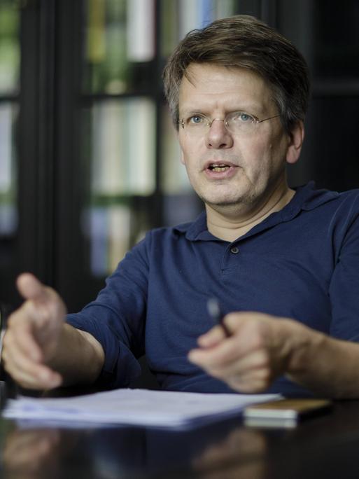Christoph Möllers sitzt an einem Tisch in einem Arbeitszimmer und diskutiert lebhaft.