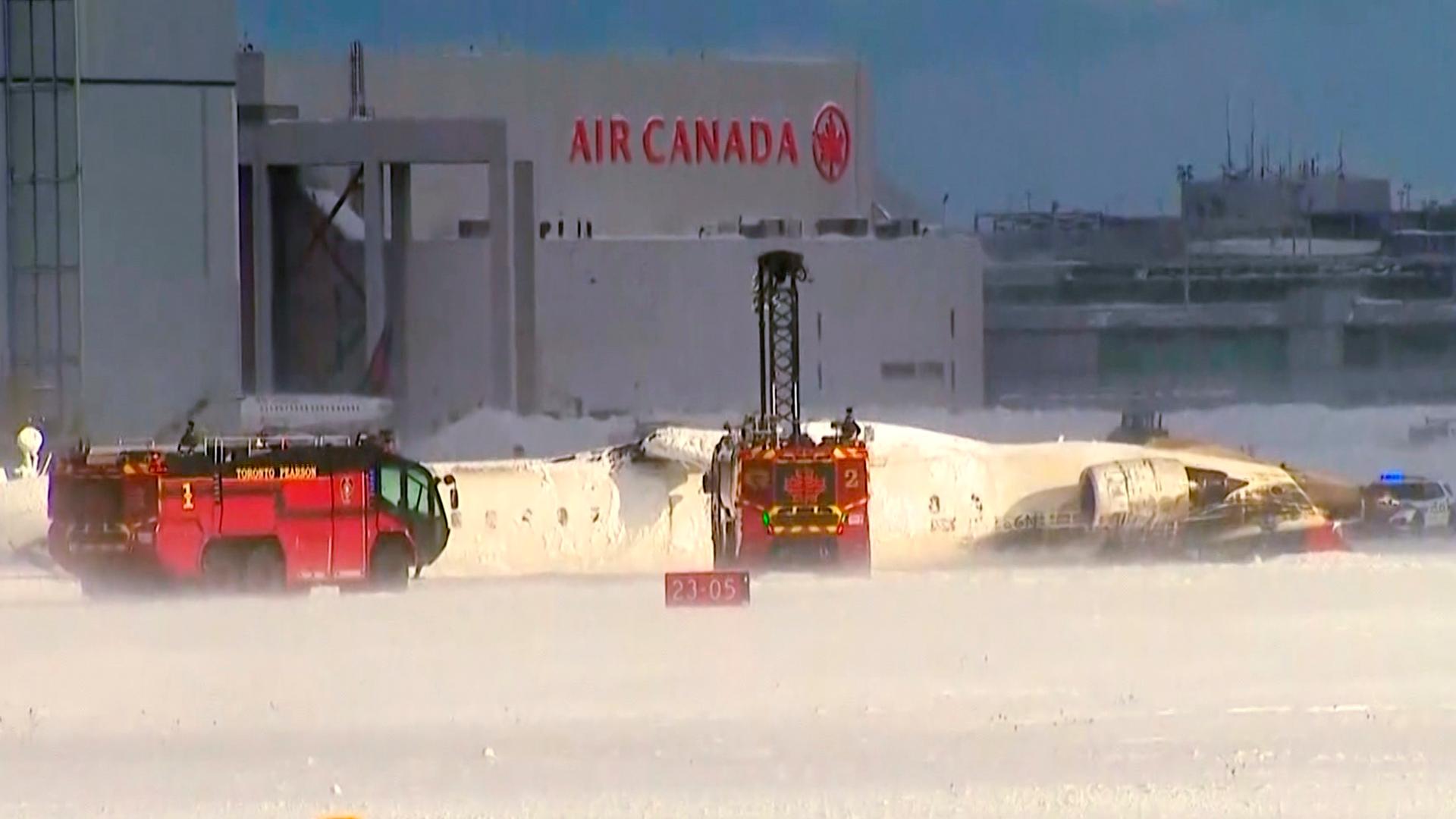 Das Bild zeigt Rettungskräfte am Toronto Pearson Airport nach der Bruchlandung eines Flugzeugs, das kopfüber auf der Landebahn zum Liegen kam.