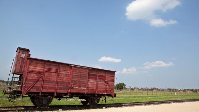 Ein Güterwagen der Deutschen Reichsbahn vor dem Stacheldrahtzaun des Vernichtungslagers Auschwitz-Birkenau.