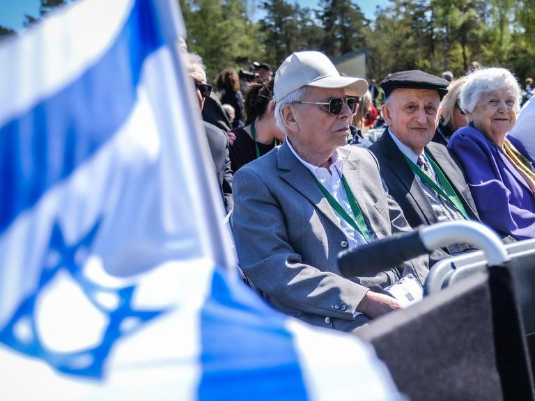 Im ehemaligen Konzentrationslager Bergen-Belsen versammeln sich hochbetagte Frauen und Männer, um der Befreiung im Frühjahr 1945 zu gedenken. Links ist die israelische Flagge mit dem Davidstern zu sehen. 