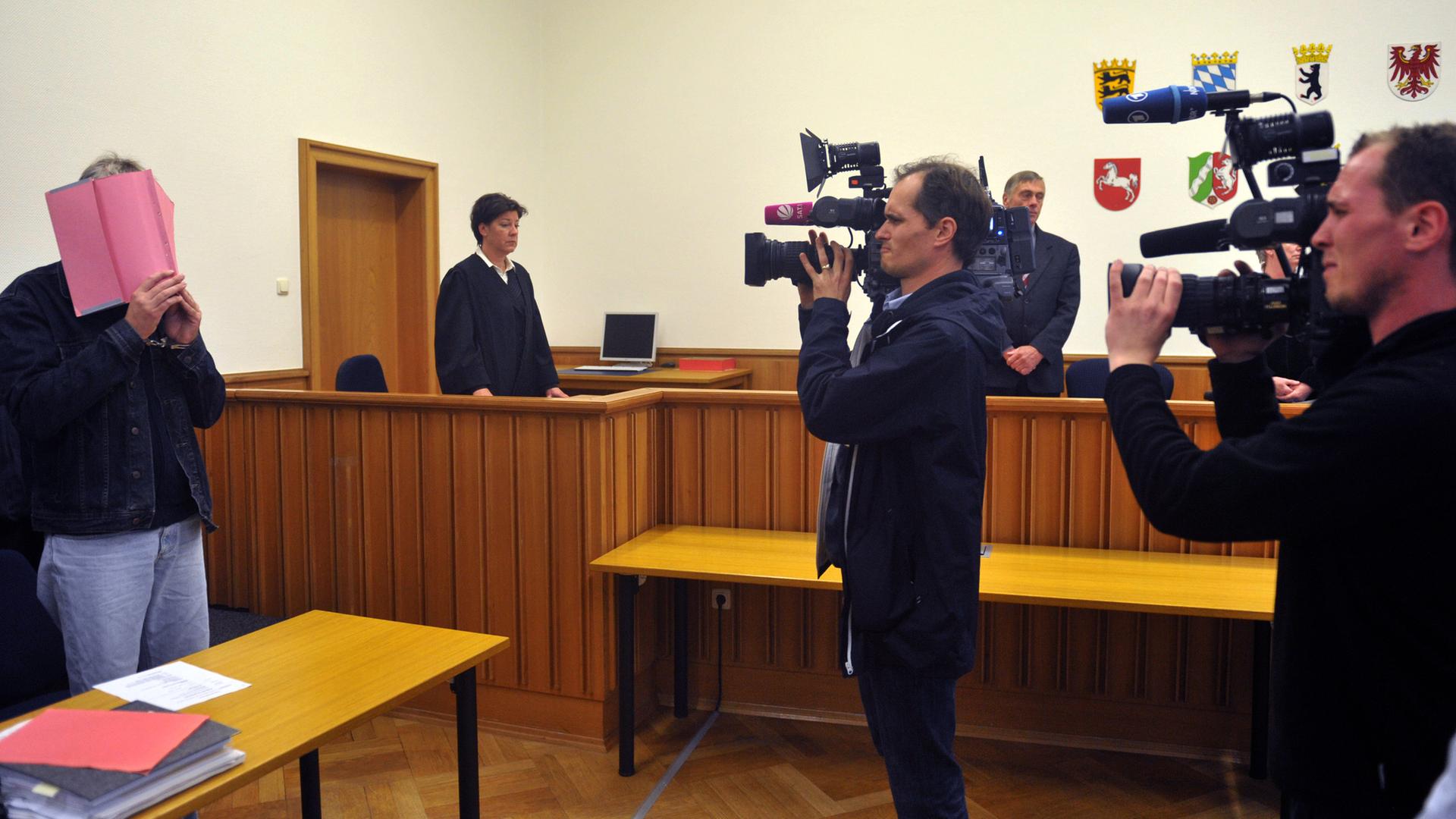 Der mutmaßliche dreifache Kindesmörder Martin N. steht am 10.10.2011 mit einem Ordner verdeckt beim Eintreffen des Gerichts im Verhandlungsaal des Landgericht Stade und wird gefilmt.