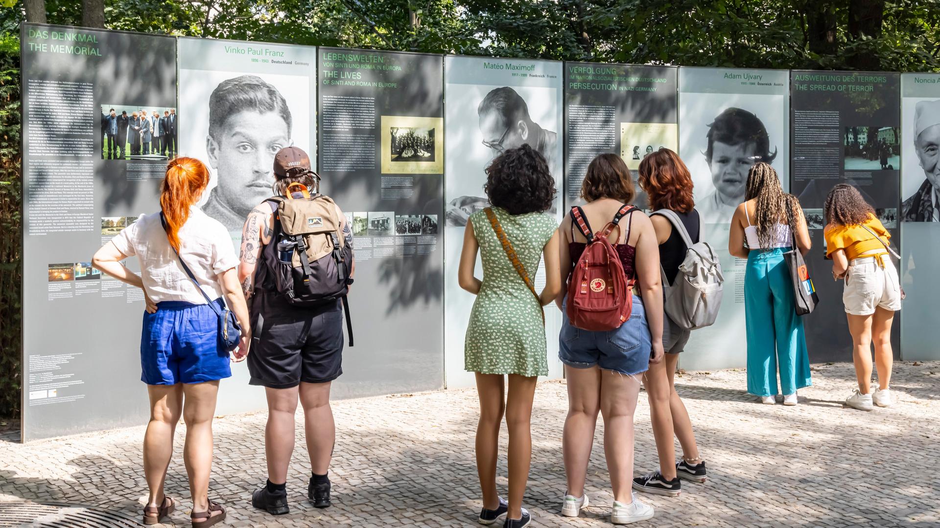 Junge Menschen stehen vor einer Gedenk-Stätte im Tier-Garten in Berlin