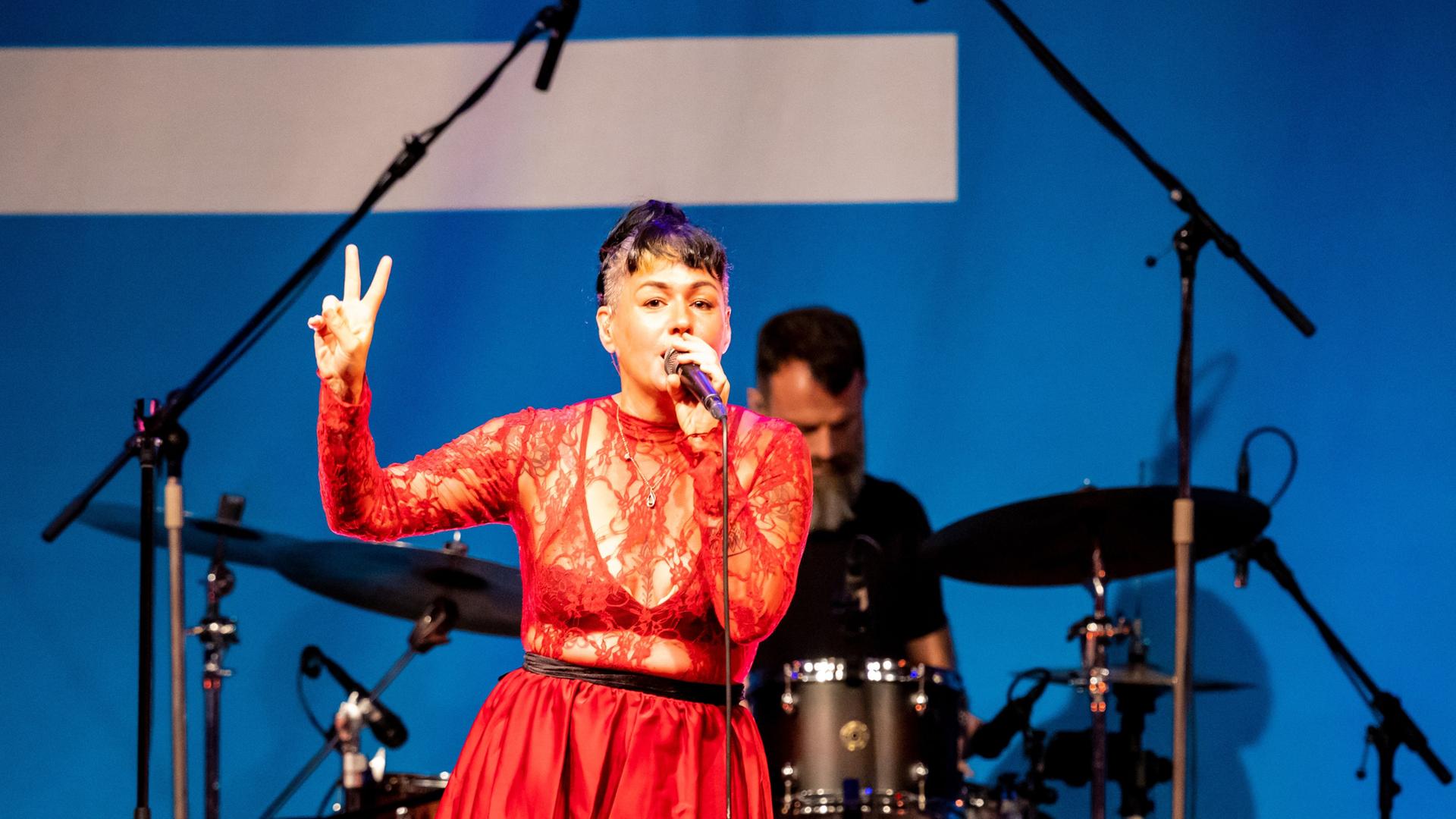 Sängerin Meghan Parnell steht in einem roten Spitzenoberteil auf der Bühne im Deutschlandfunk Kammermusiksaal und singt, während sie tanzt.