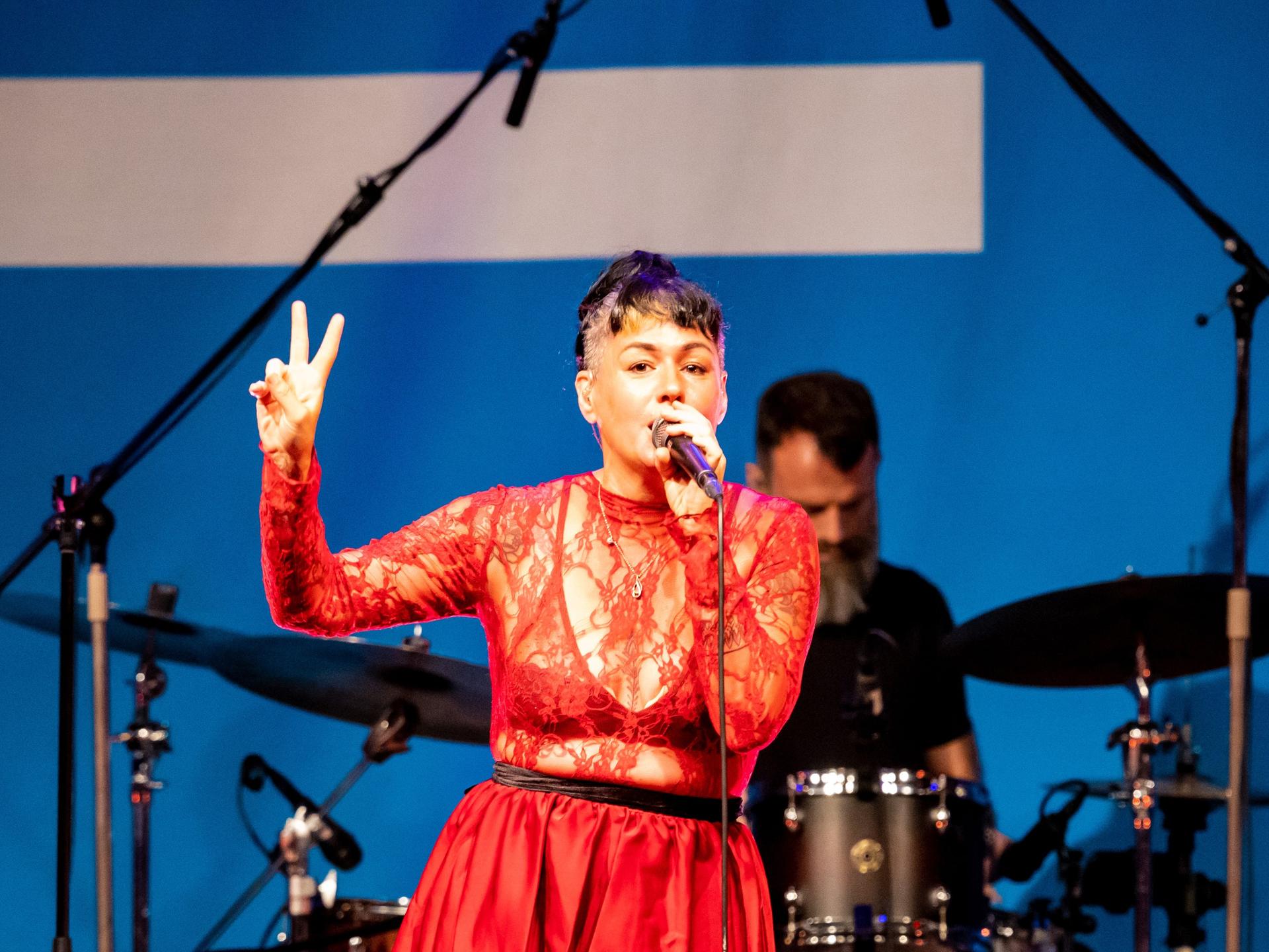 Sängerin Meghan Parnell steht in einem roten Spitzenoberteil auf der Bühne im Deutschlandfunk Kammermusiksaal und singt, während sie tanzt.