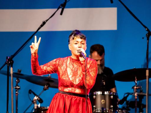 Sängerin Meghan Parnell steht in einem roten Spitzenoberteil auf der Bühne im Deutschlandfunk Kammermusiksaal und singt, während sie tanzt.