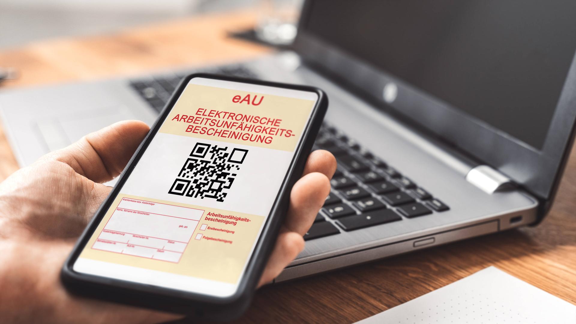 Eine Hand hält ein Smartphone mit einer elektronischen Arbeitsunfähigkeitsbescheinigung, eAU. Eine Hand hält ein Smartphone mit einer elektronischen Arbeitsunfähigkeitsbescheinigung, eAU.