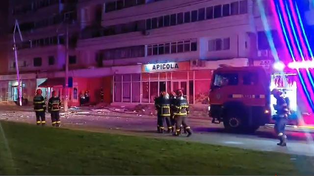 Trümmer liegen vor einem Haus. Daneben stehen Einsatz-Kräfte von der Feuerwehr.