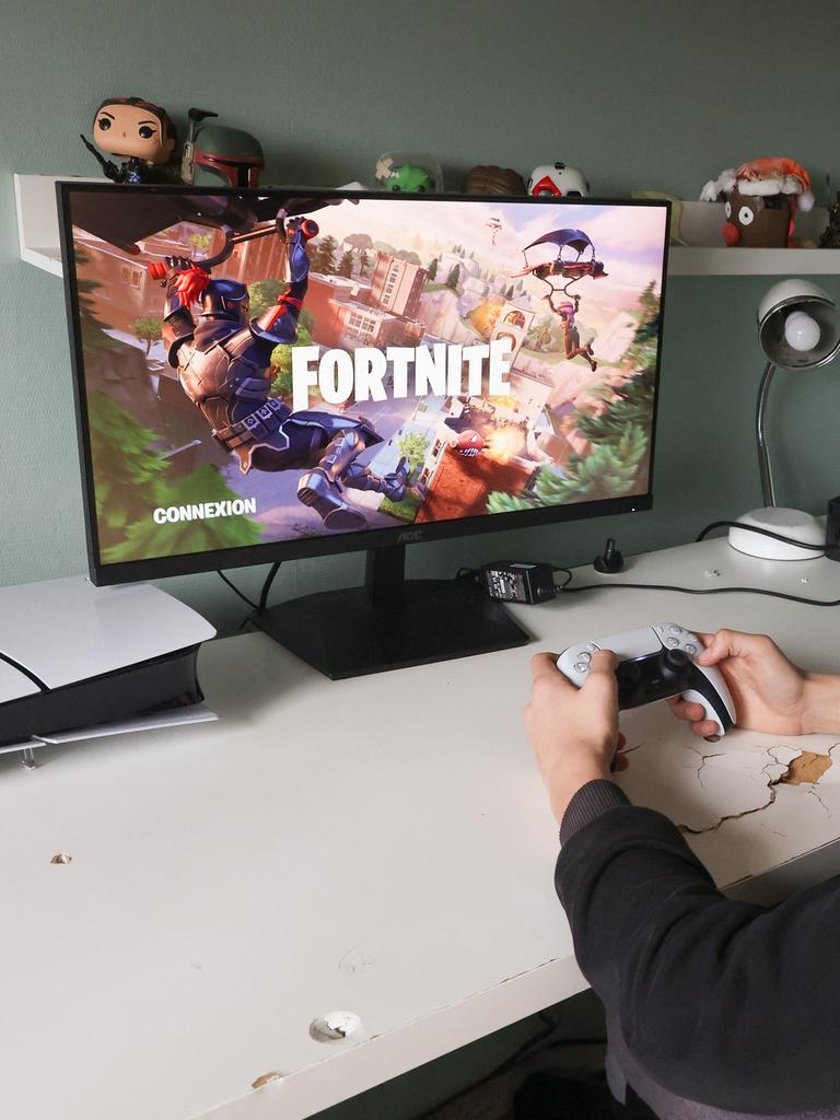 Ein Teeanager sitzt mit Controller in der Hand vor einem Bildschirm und spielt das Computerspiel Fortnite.
