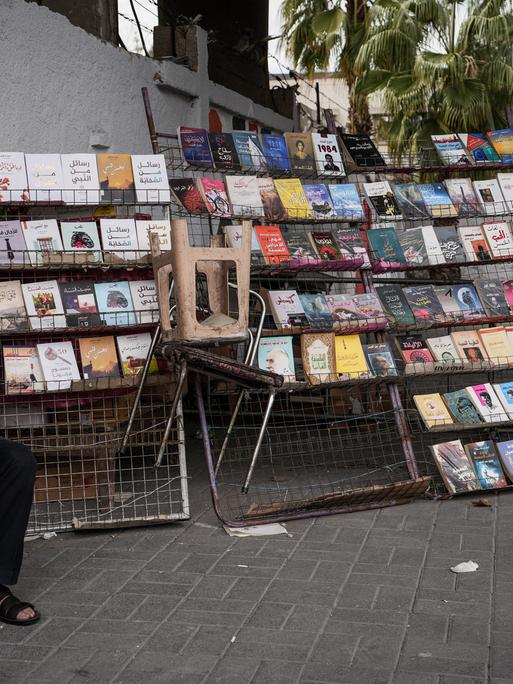 Ein syrischer Buchhändler sitzt neben seinem Bücherstand auf dem Bürgersteig in Damaskus. Aufnahmedatum: März 2025.