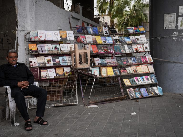 Ein syrischer Buchhändler sitzt neben seinem Bücherstand auf dem Bürgersteig in Damaskus. Aufnahmedatum: März 2025.