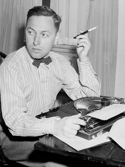 Der US-amerikanische Dramatiker Tennessee Williams an einem Tisch mit Schreibmaschine sitzend und Zigarette rauchend