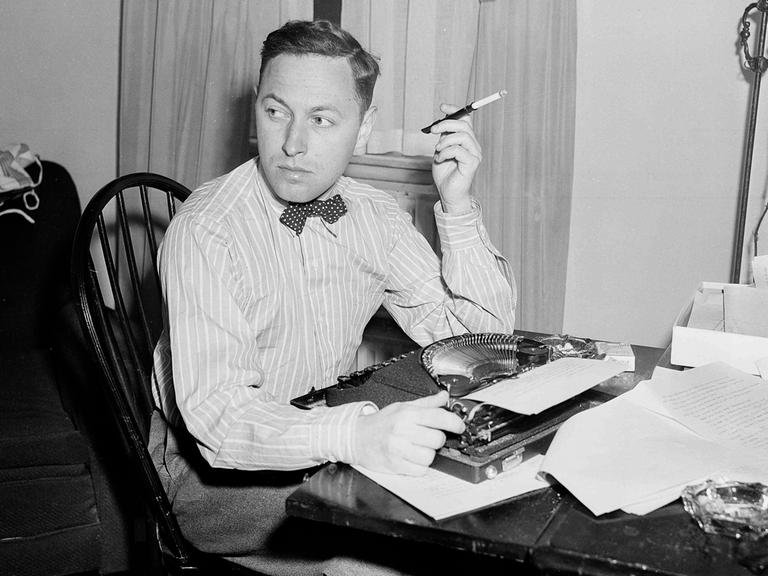 Der US-amerikanische Dramatiker Tennessee Williams an einem Tisch mit Schreibmaschine sitzend und Zigarette rauchend