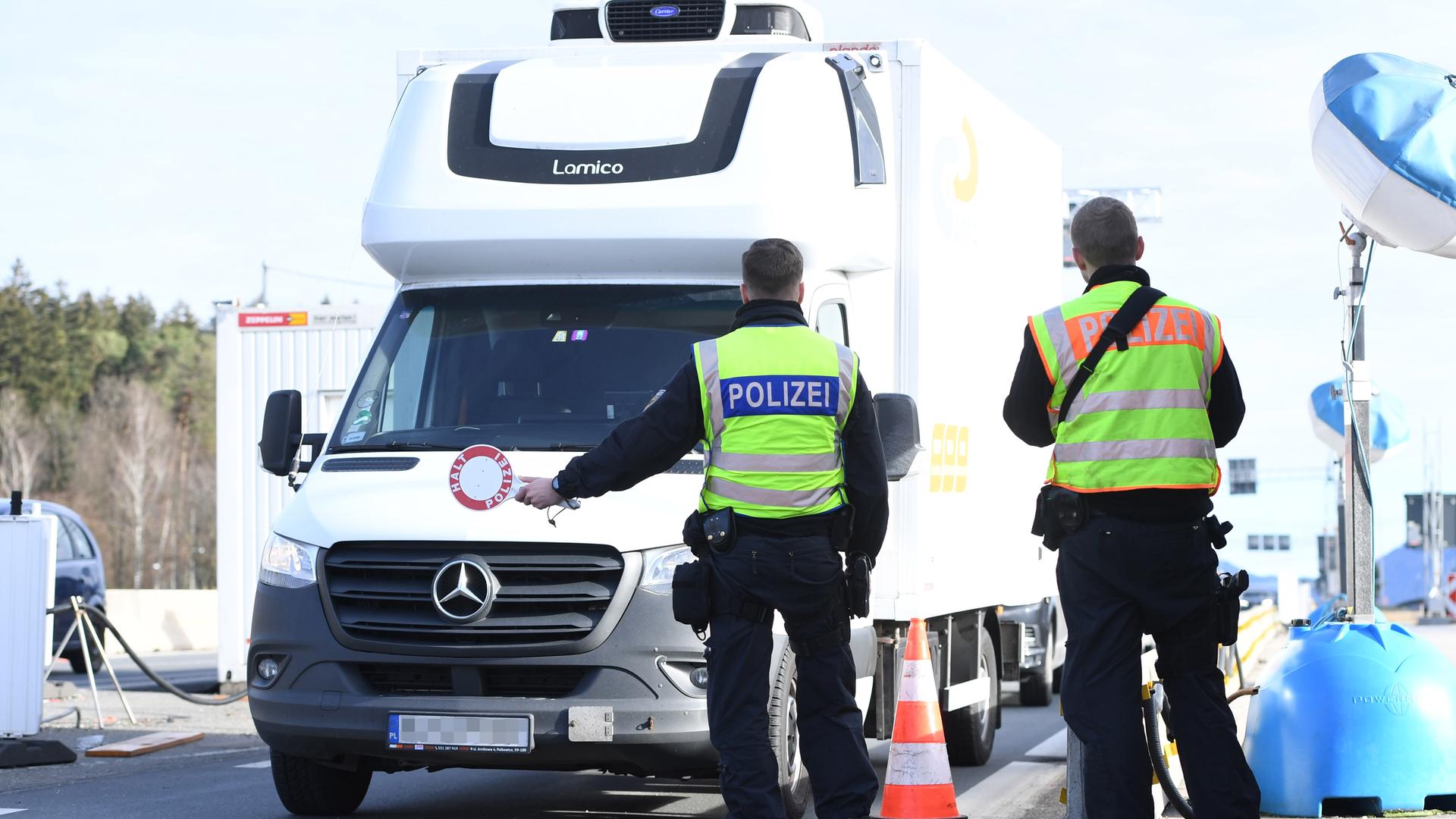Zwei Polizisten winken einen Wohnwagen zur Grenzkontrolle an der deutsch-österreichischen Grenze am 29.12.2022 am Grenzübergang Walserberg.