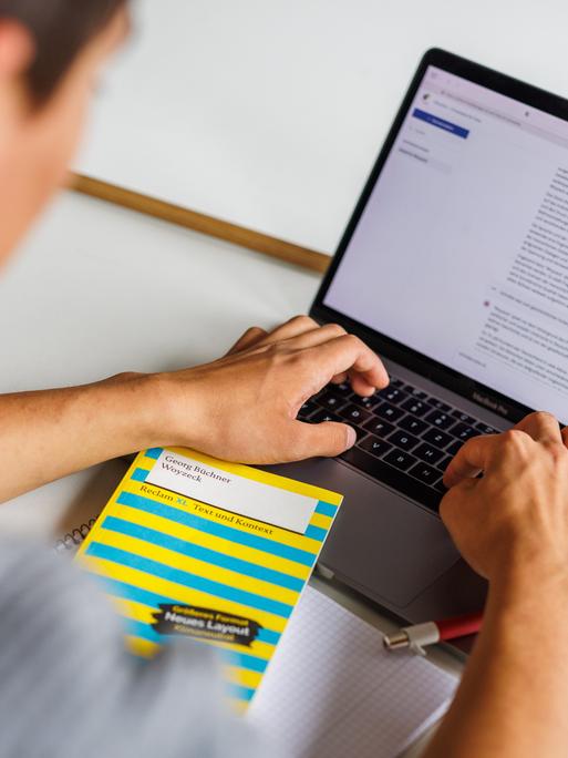 Ein Schüler sitzt vor einem Laptop und benutzt ein KI-Tool.