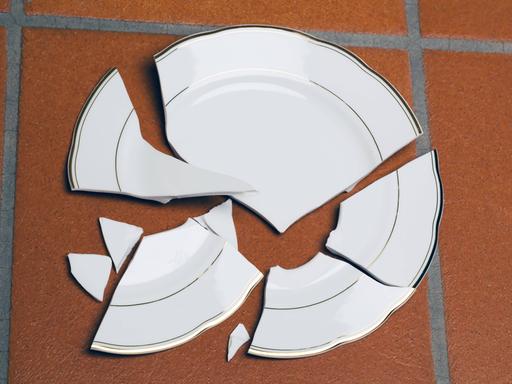 Ein zerbrochener Teller liegt auf einem Fuboden