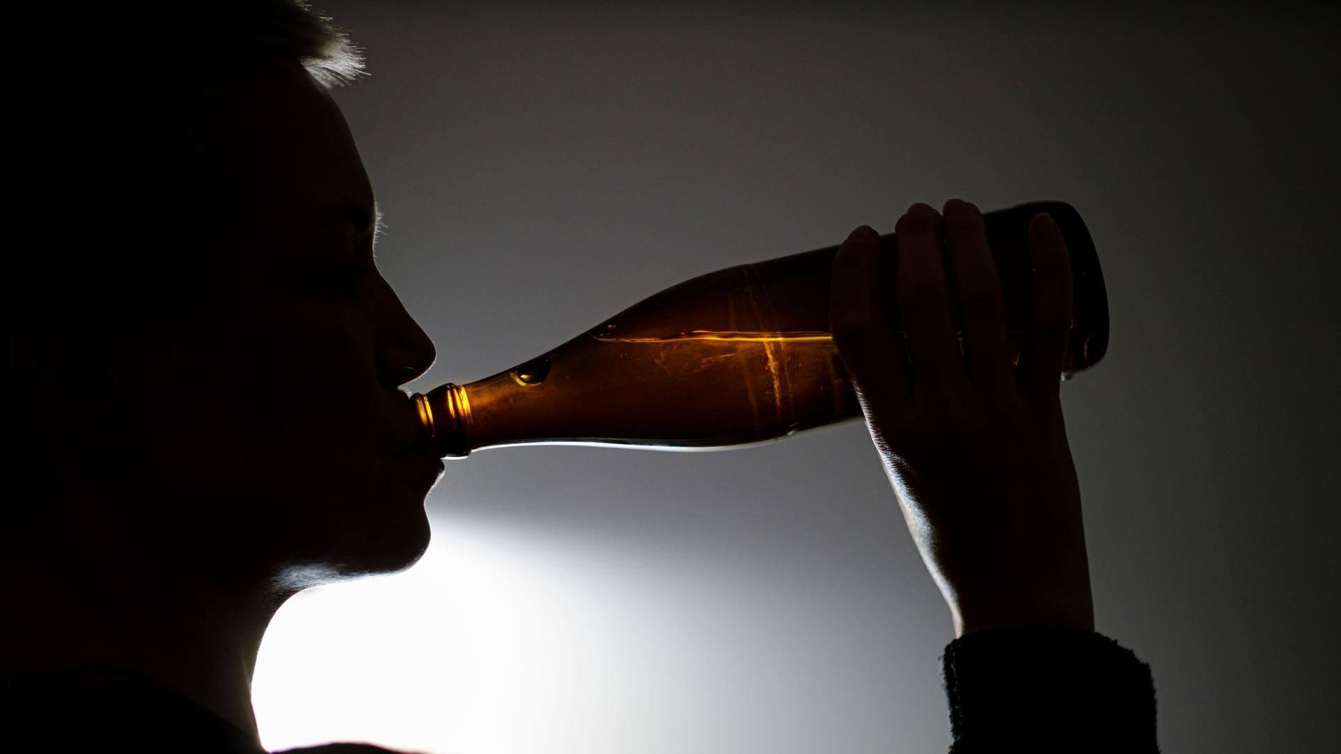 Eine Frau trinkt aus einer Flasche Bier. Eine Frau trinkt aus einer Flasche Bier.