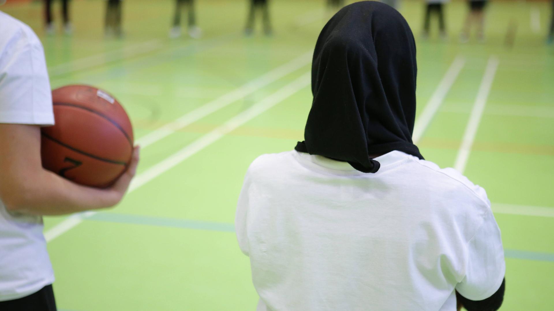 Ein Mädchen mit Kopftuch beim Basketball-Training.