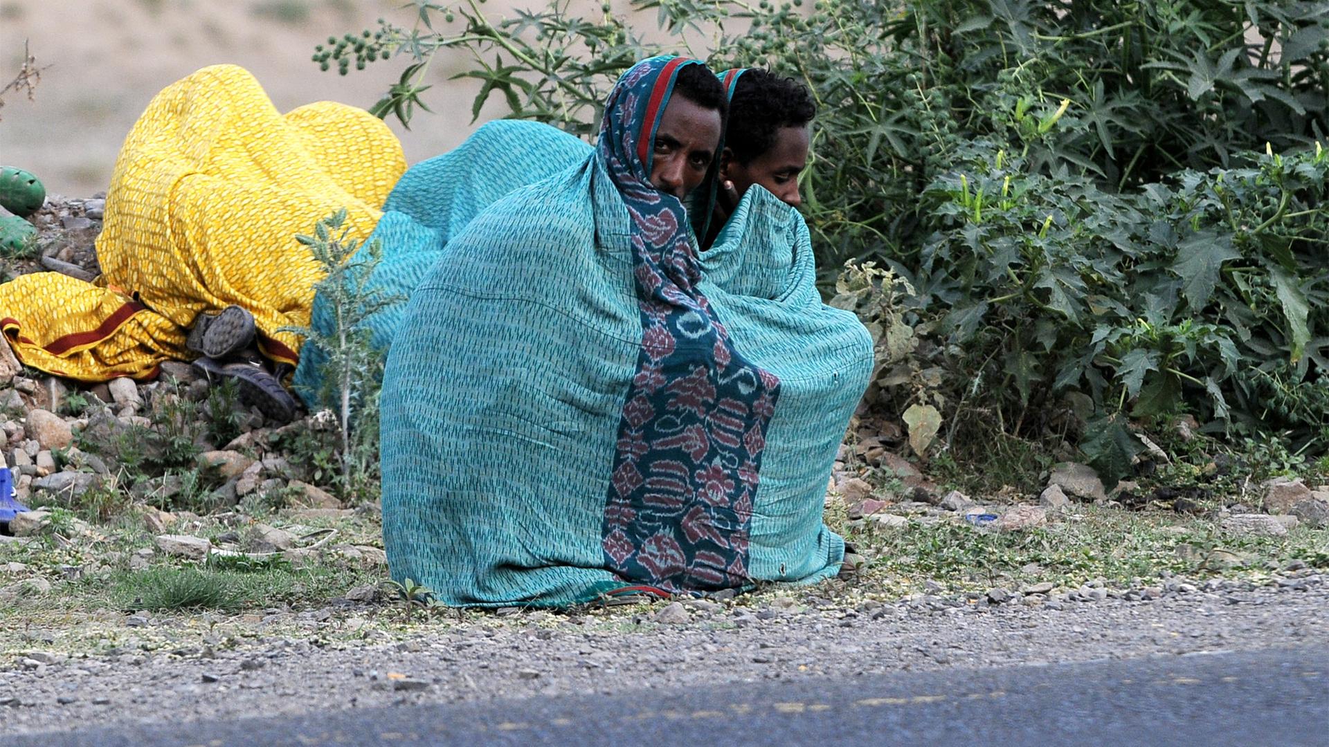 Äthiopische Migranten sitzen am Straßenrand. 