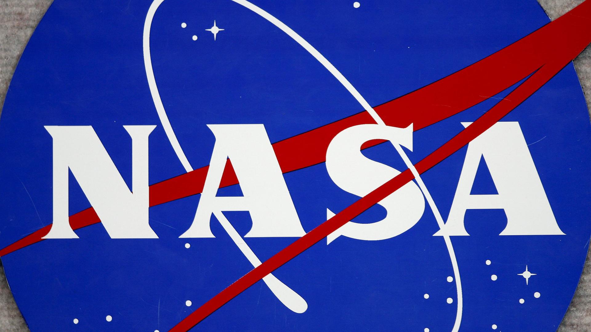 Das Logo der NASA: Ein weißer Schriftzug inmitten eines blauen Universums mit symbolhaft dargestellten Sternen