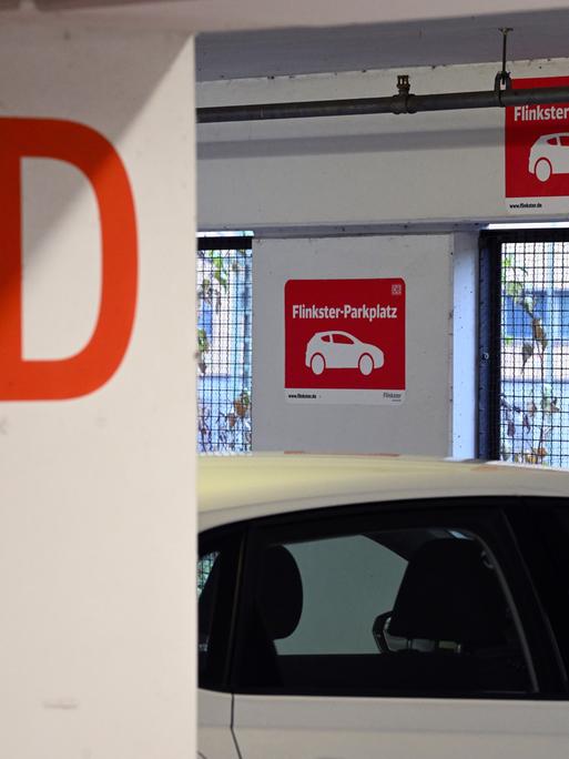 Schilder mit dem roten Logo für "Flinkster-Parkplatz" ist in dem Parkhaus am Hauptbahnhof vor einer Parkbucht angebracht.