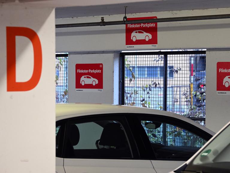 Schilder mit dem roten Logo für "Flinkster-Parkplatz" ist in dem Parkhaus am Hauptbahnhof vor einer Parkbucht angebracht.