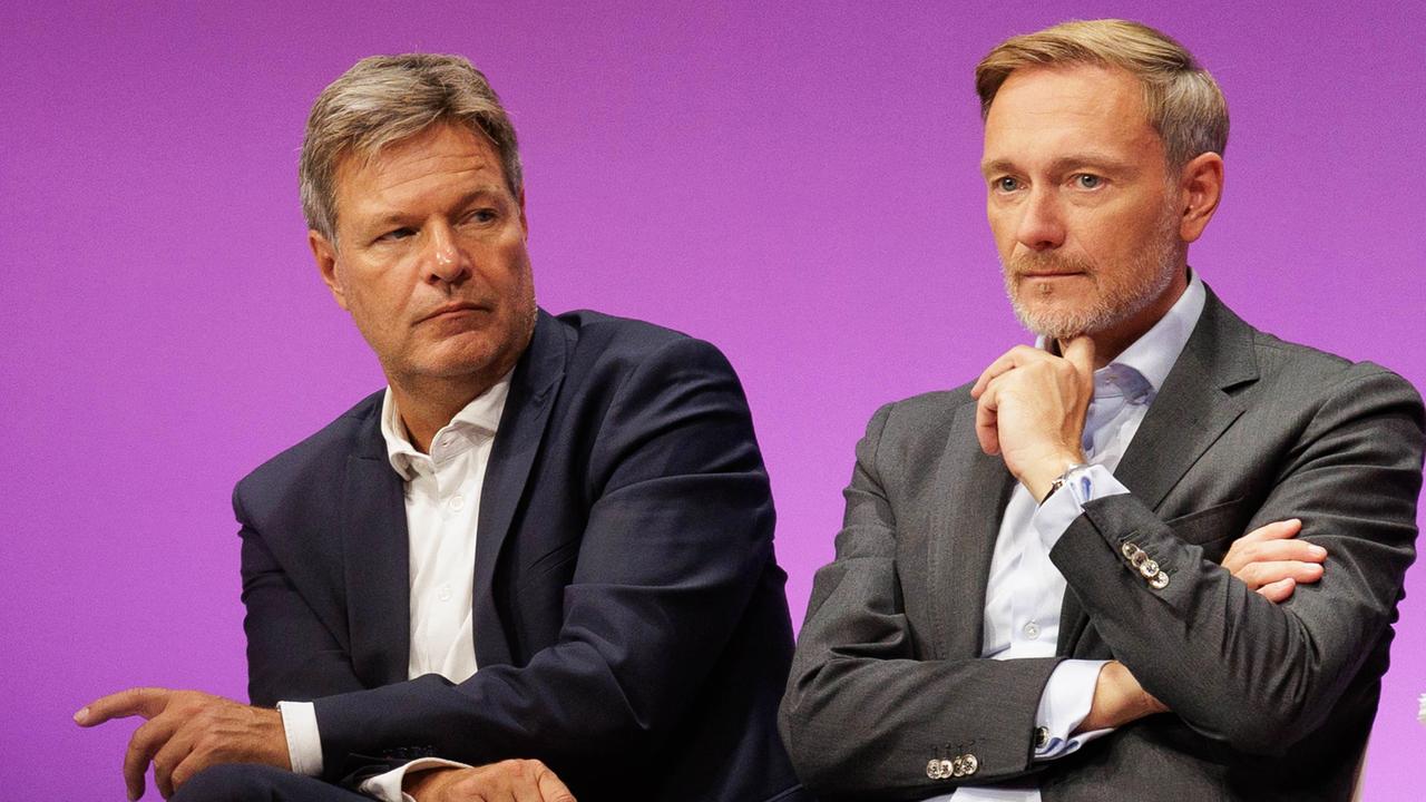 Bundeswirtschaftsminister Robert Habeck und Bundesfinanzminister Christian Lindner sitzen auf einem Podium und gucken beide nachdenklich.