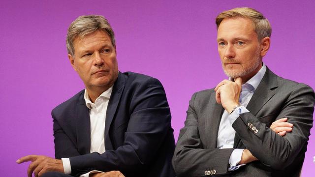 Bundeswirtschaftsminister Robert Habeck und Bundesfinanzminister Christian Lindner sitzen auf einem Podium und gucken beide nachdenklich.