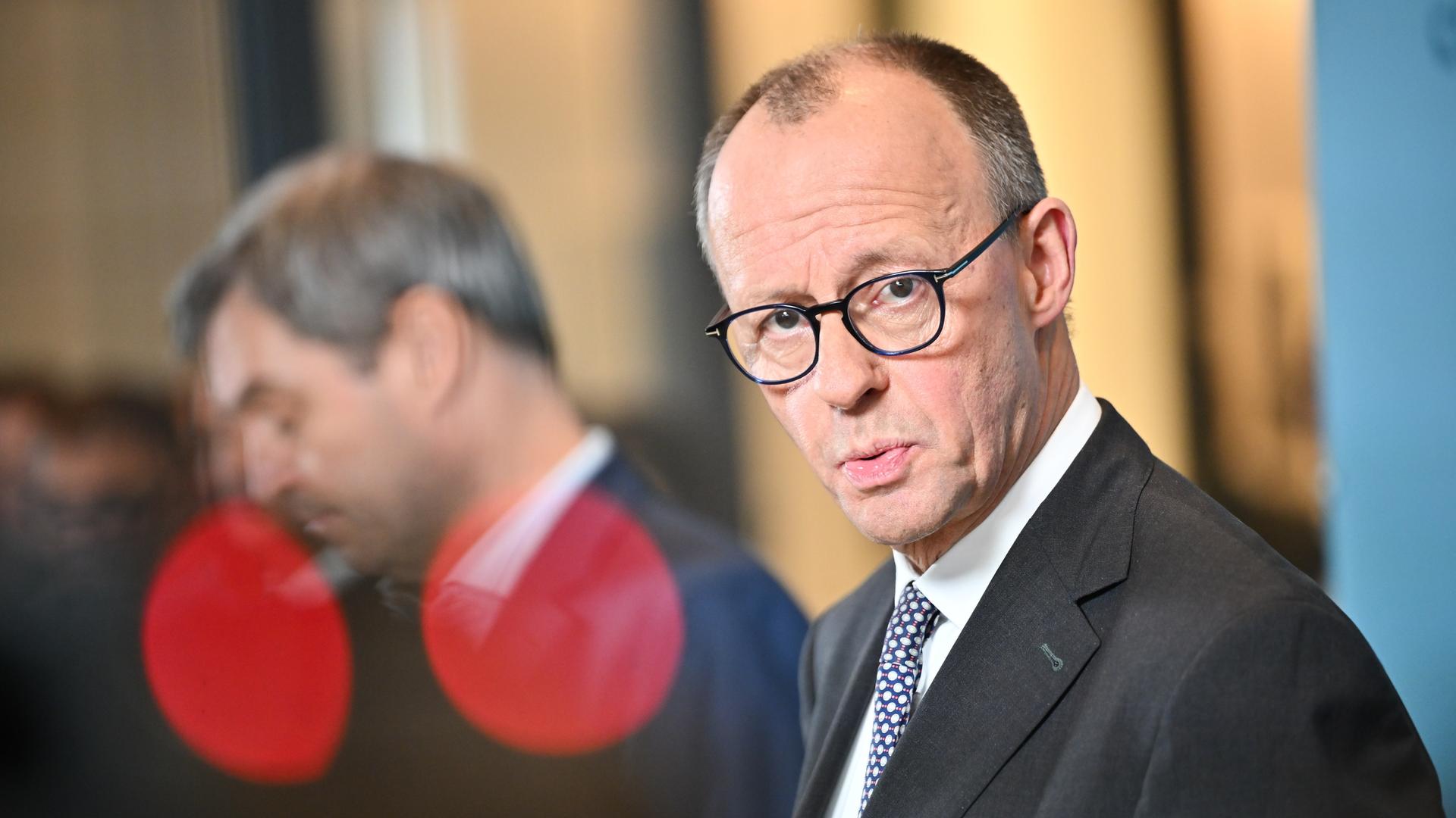 Friedrich Merz (r), CDU-Bundesvorsitzender und CDU/CSU-Fraktionsvorsitzender im Bundestag, und verschwommen dahinter Markus Söder, CSU-Parteivorsitzender und Ministerpräsident von Bayern