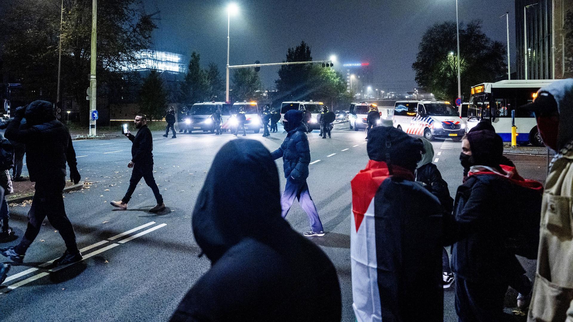 Demonstranten  stehen mit einer palästinensischen Flagge vor einer Polizeieinheit bei einer pro-palästinensischen Demonstration während des Spiels Ajax - Maccabi Tel-Aviv am Anton de Komplein.