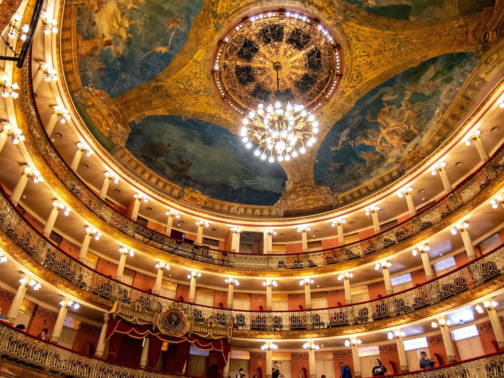 Blick in den Innenraum des Opernhauses in Manaus mit seinem imposanten Deckengemälde, Kronleuchter und vielen schmucken Rängen.