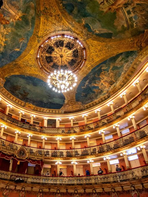 Blick in den Innenraum des Opernhauses in Manaus mit seinem imposanten Deckengemälde, Kronleuchter und vielen schmucken Rängen.