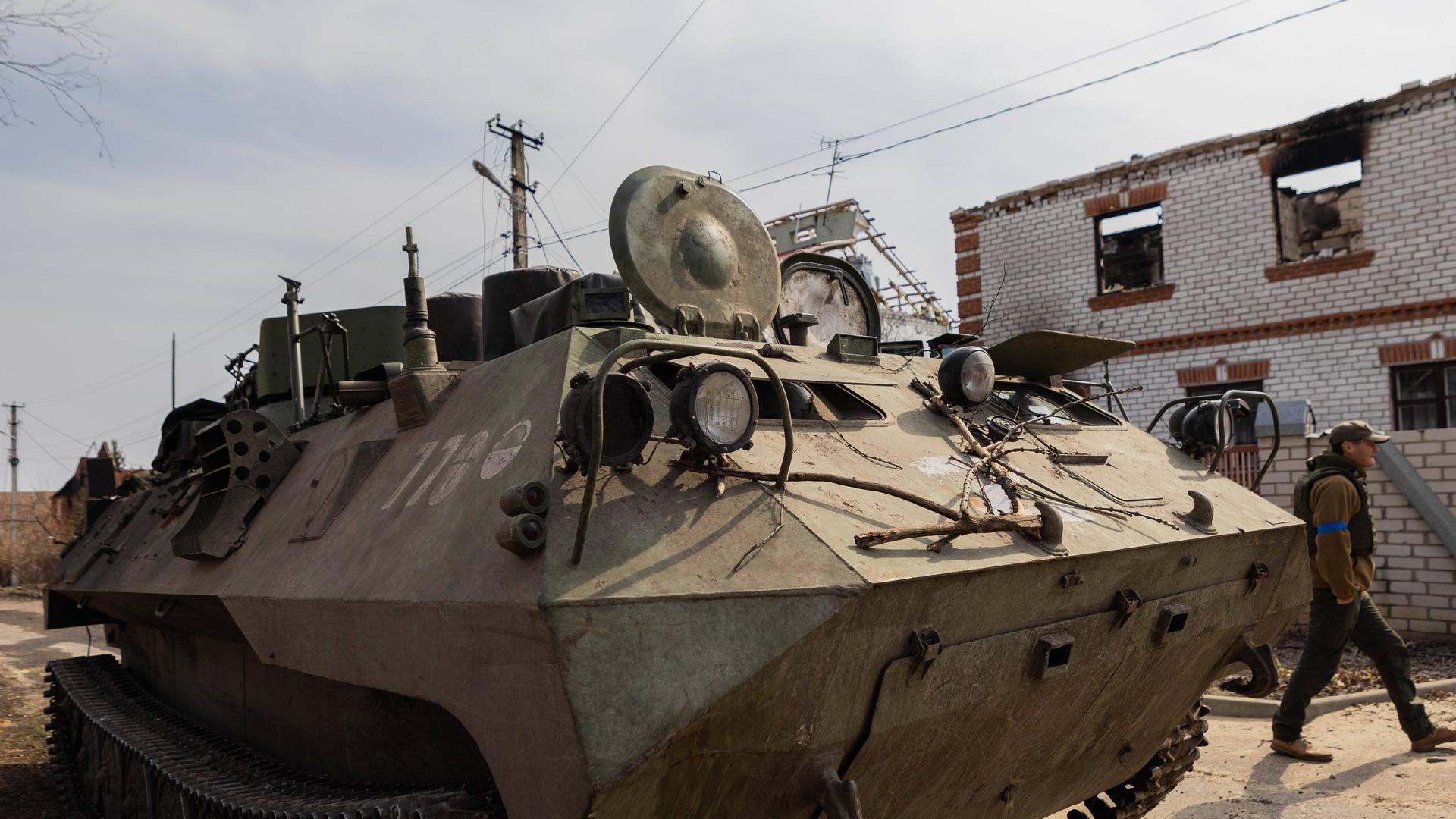 Ukrainische Soldaten laufen an einem eroberten russischen Panzer vorbei. Ukrainische Soldaten laufen an einem eroberten russischen Panzer vorbei.