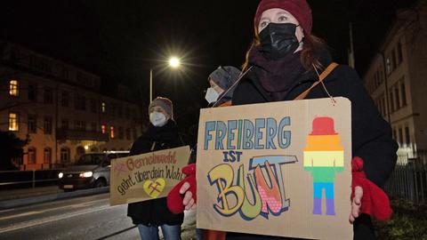 Eine Frau steht mit einem Schild in der Hand mit dem Text "Freiberg ist bunt"