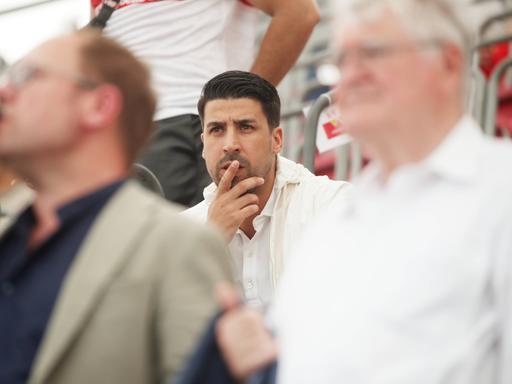 Sami Khedira sitzt nachdenklich auf der Tribüne und schaut sich ein Fußballspiel an.