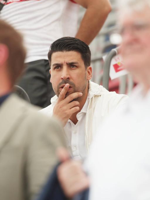 Sami Khedira sitzt nachdenklich auf der Tribüne und schaut sich ein Fußballspiel an.