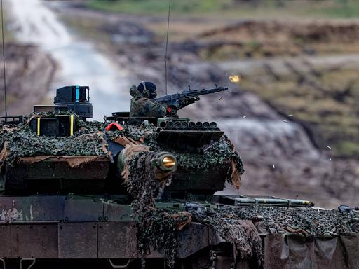 Auf dem Bild feuert ein Soldat aus einer Bordwaffe des Leopard 2A6 Kampfpanzer. 